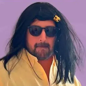 Víctor como Loco Piña, con peluca negra larga y anteojos de sol